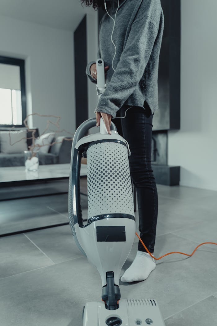 services-02 Focused shot of a woman vacuuming a stylish living room, emphasizing cleanliness.