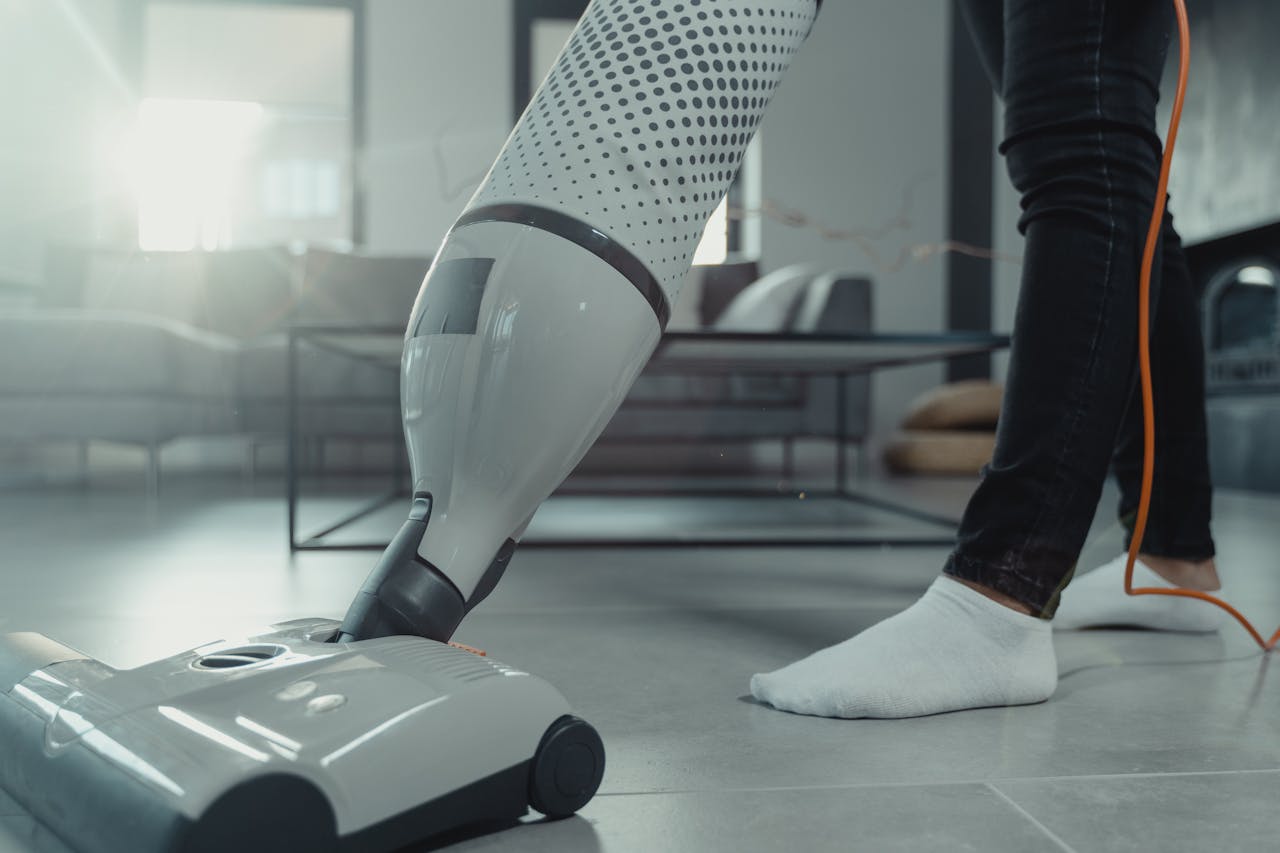 Person vacuuming a tiled floor with a modern appliance in a bright indoor setting.